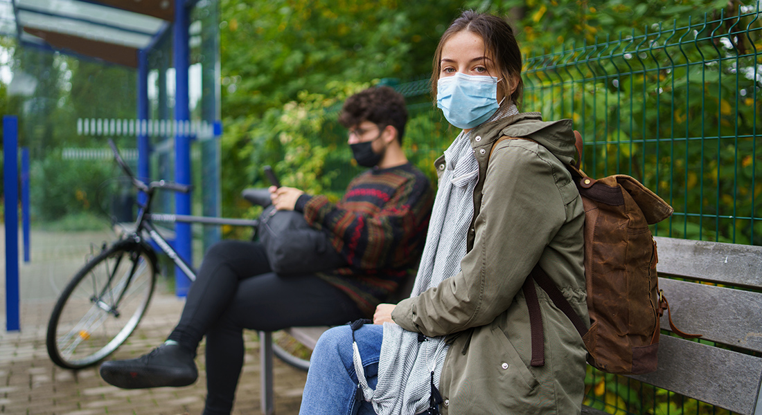 People with masks waiting for a bus